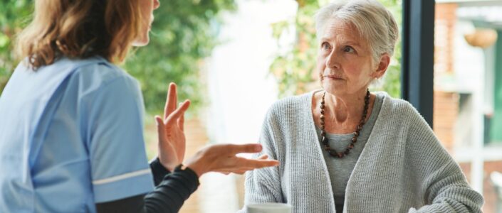 Oudere vrouw luister aandachtig naar vrouwelijke zorgmedewerker