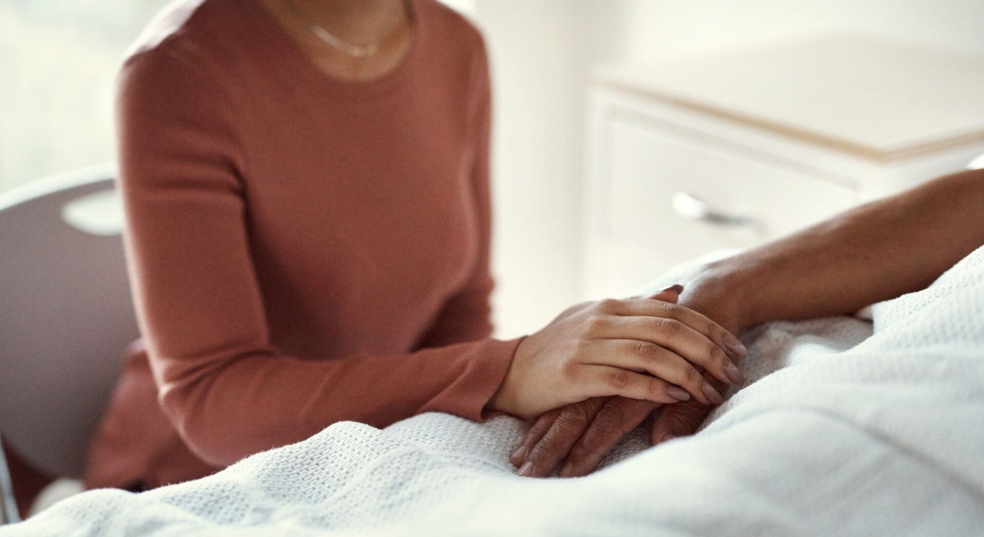 Vrouw die hand vasthoudt van iemand in bed