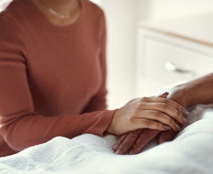 Vrouw die hand vasthoudt van iemand in bed