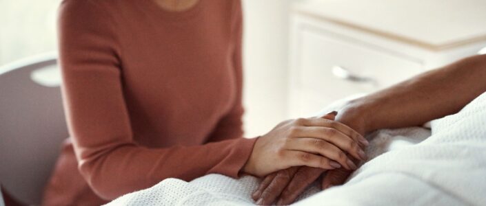 Vrouw die hand vasthoudt van iemand in bed